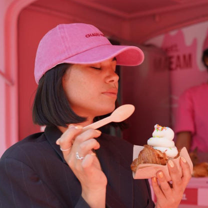 Une cliente savourant notre glace-cornet-croissant, une casquette denim rose 'Chaud Time' sur la tête